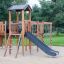 Cấu trúc leo trèo ngoài trời bằng gỗ Romping Cottage với cầu trượt và lưới dây cho trẻ em.