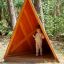 Tipi Nature wooden house bằng gỗ hình tam giác với trẻ nhỏ đứng bên trong.