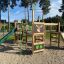 Forest Castle with slide bằng gỗ với cầu trượt xanh và các chi tiết trang trí hình lá và con nai.