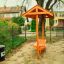 Dog Waste Bin màu đen gắn trên cột gần khu vực sân chơi trẻ em.