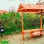 Dog Waste Bin màu đen đặt cạnh ghế gỗ có mái che trong khu vực ngoài trời.
