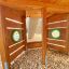 Khu vực chơi bằng gỗ Ship Modern Nature với cửa sổ tròn màu xanh lá cây và lớp phủ sàn bằng mùn cưa.