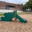 Cầu trượt Slide with Dragon Back màu xanh lá trên sân chơi cát.